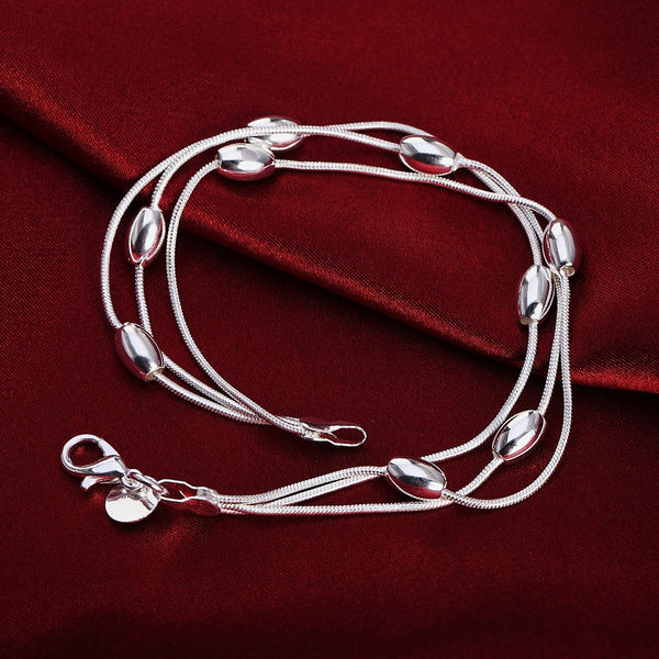 Pulsera de cuentas con dijes en color plata.
